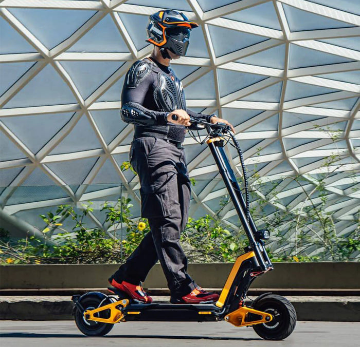 Male rider in protective gear riding an INMOTION RS electric scooter beside modern architecture